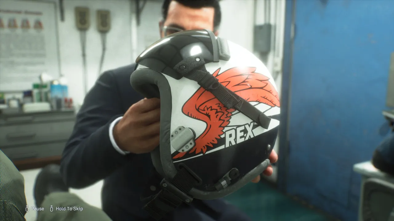A person holding a flight helmet painted with a red and white bird and the word REX
